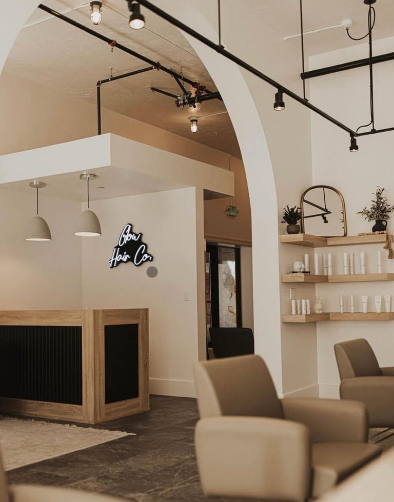 Modern interior of a salon space with arched ceilings, pendant lights, wooden shelving, beige furniture, and a reception desk