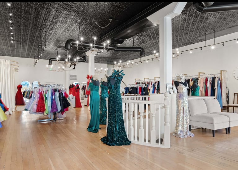 Modern boutique interior with colorful dresses displayed on racks and mannequins throughout spacious showroom with wooden floors and industrial ceiling